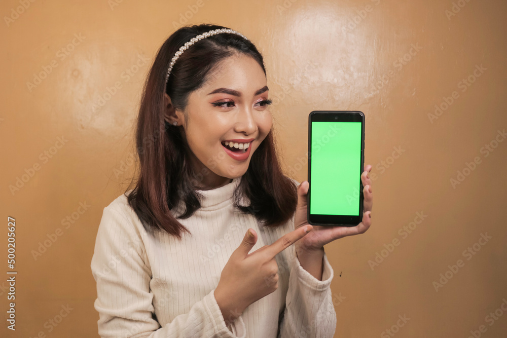 Happy and smiling young asian women showing a green blank screen stock