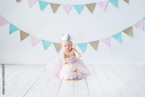 Little baby girl eating birthday cake during cake smash party