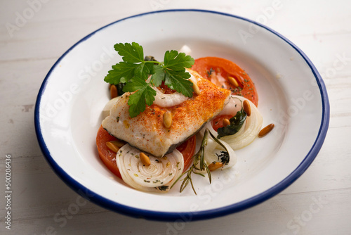 Baked hake with tomato and onion. Spanish traditional tapas.