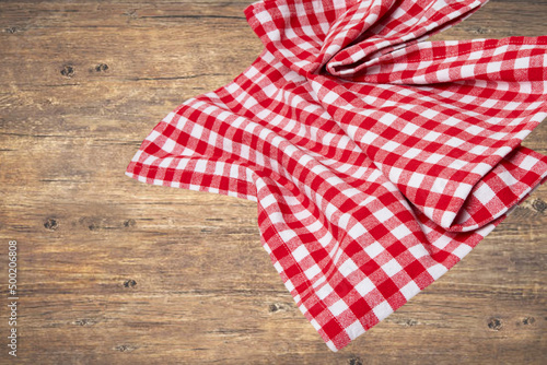 Empty table product. Top view of a rustic wooden table with a red and white checkered tablecloth or napkin. Template for your food and product display montage. Space for food recipe.