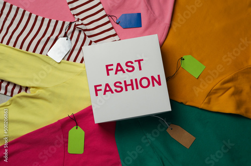 White box with phrase Fast Fashion and different clothes, top view