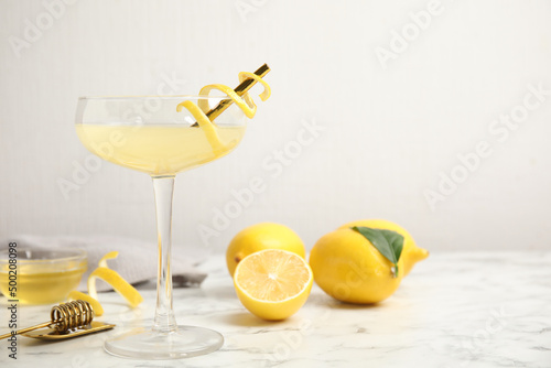 Delicious bee's knees cocktail and ingredients on white marble table. Space for text