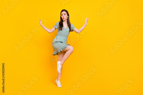 Photo of excited impressed lady dressed green dress dancing looking empty space isolated yellow color background