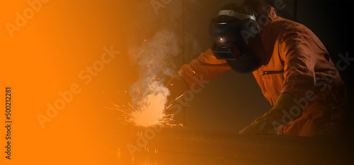 Metal industry worker are welding steel sheet for real estate projects received. Sparkler on black background, close-up. Heavy work in factory.
