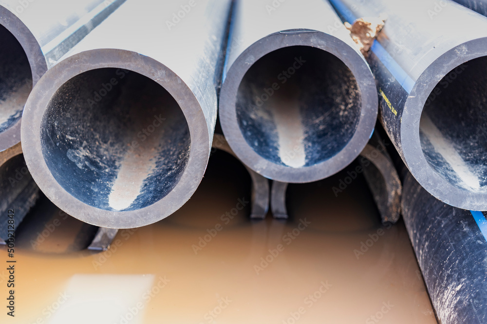 Water pipes for drinking water supply lie on the construction site. Preparation for earthworks for laying an underground pipeline. Modern water supply systems for a residential city. Water pipes for drinking water supply lie on the construction site. Preparation for earthworks for laying an underground pipeline. Modern water supply systems for a residential city.