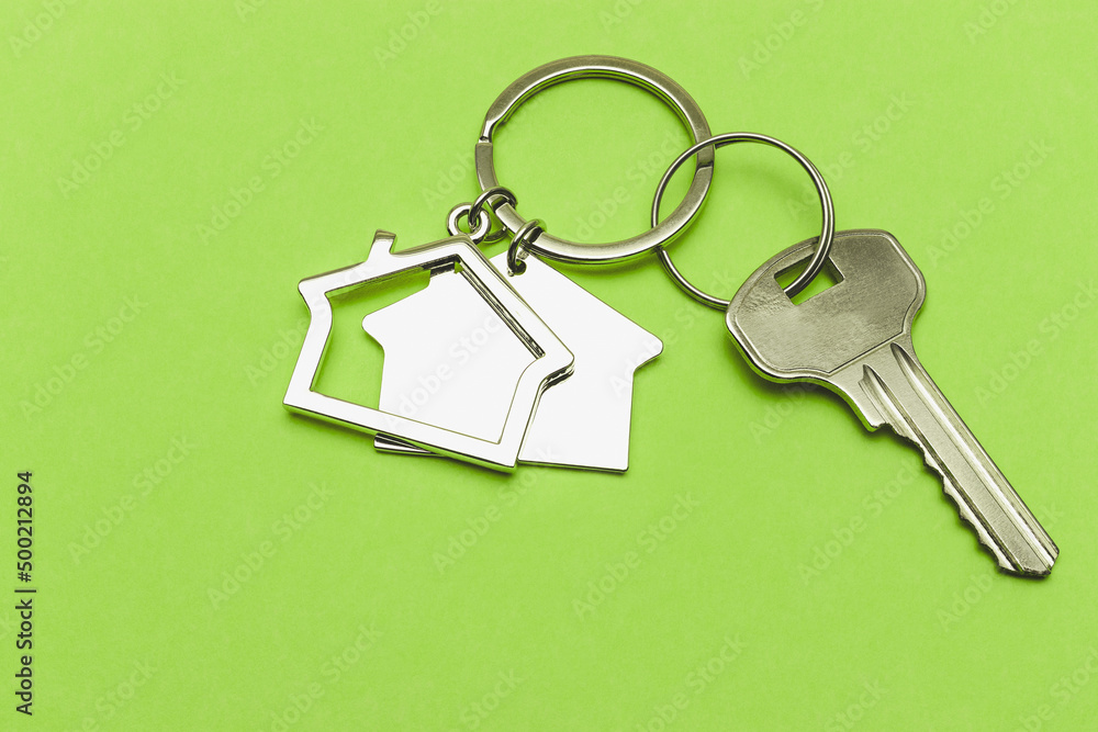 The concept of mortgage and rental housing and real estate. Mortgage credit lending. Keychain in the shape of a house with a key on a light green background. The concept of mortgage and rental housing and real estate. Mortgage credit lending. Keychain in the shape of a house with a key on a light green background.