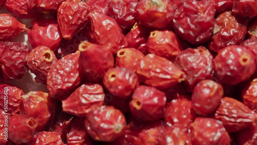 Rosa canina or rubiginosa berries footage. Dry fruits of sweet-brier on white surface video, briar rose hip or rosehip, also called rose haw and rose hep motion, the accessory fruit of rose plant.  photo