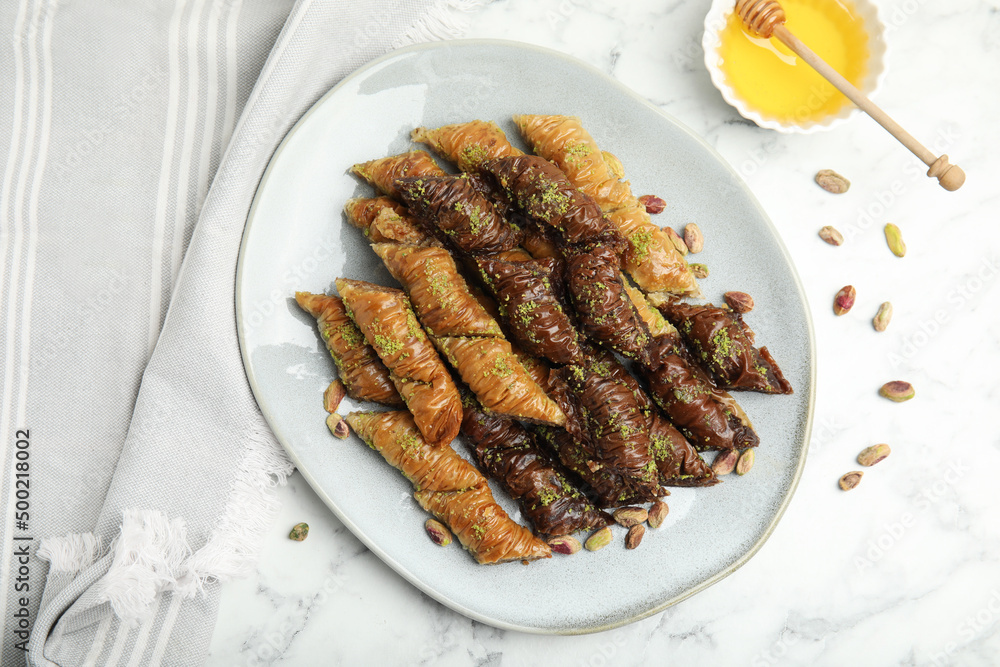 Delicious baklava with pistachio nuts and honey on white marble table, flat lay Delicious baklava with pistachio nuts and honey on white marble table, flat lay