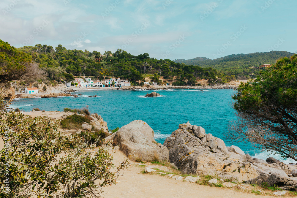 Main view of cala s'Alguer, a lovely beach surrounded by traditional fishermen's white buildings with colorful doors and windows, Palamos, Costa Brava, Girona, Catalonia, Spain