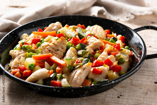 Chicken stir fry and vegetables on wooden table 