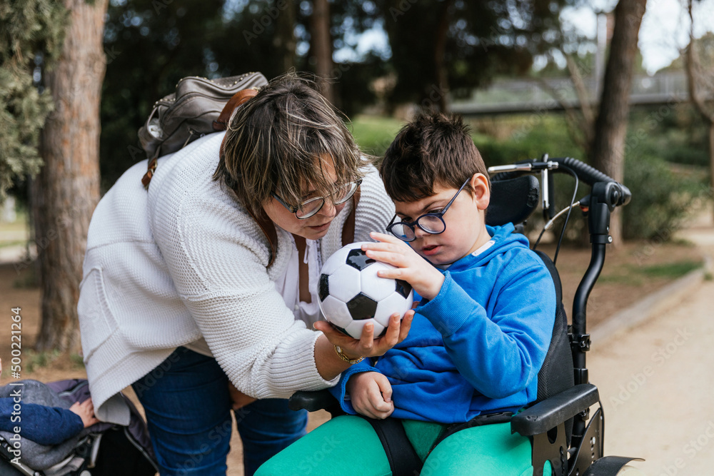 Child with multiple disabilities in a wheelchair playing with a soccer