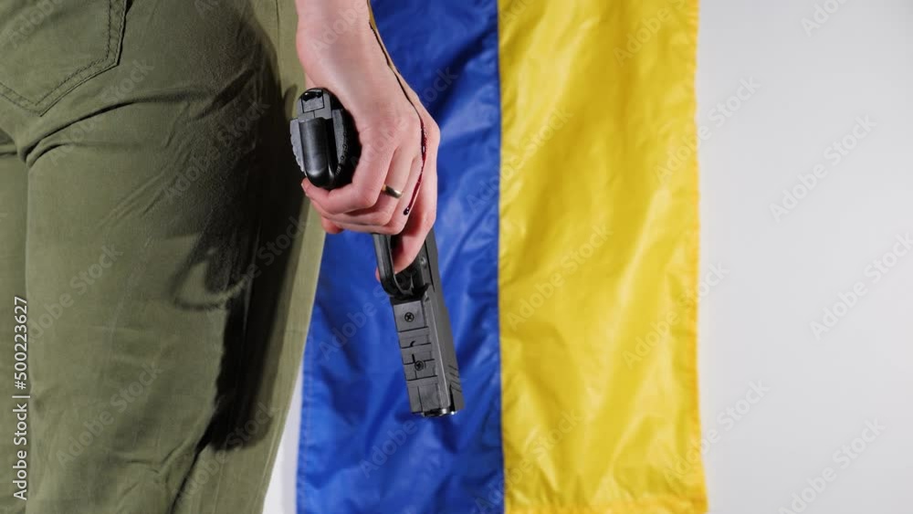 a girl in green pants holds a gun in her hand through which blood flows against the background of the flag of Ukraine a girl in green pants holds a gun in her hand through which blood flows against the background of the flag of Ukraine