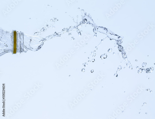 Splash of water from a bottle on a white background. Reflection on the surface of the water.
