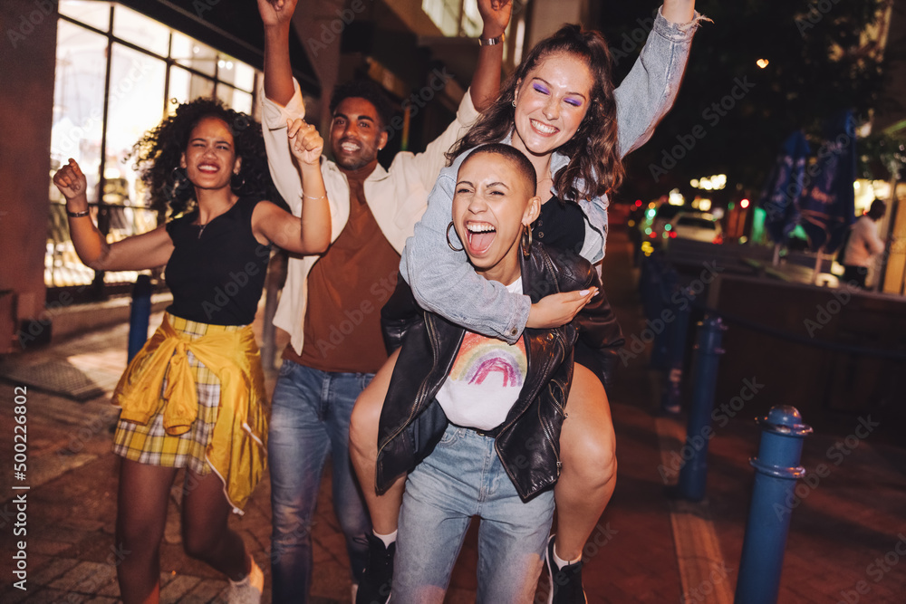 Naklejka premium Cheerful young woman piggybacking her friend in the city