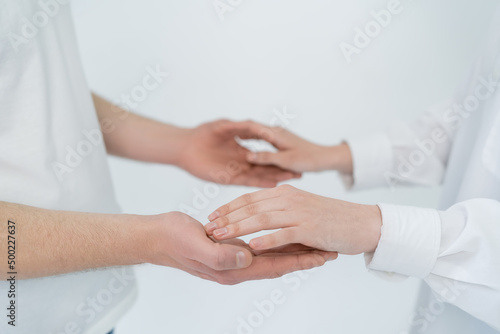 Cropped view of young couple holding hands isolated on white.