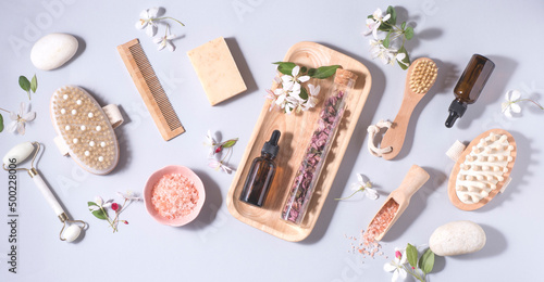 Natural cosmetics product background, banner with small spring-summer flowers . Serum or oil and cosmetic skin care, roller, zero waste, eco friendly bathroom and spa accessories, flowers aromatherapy
