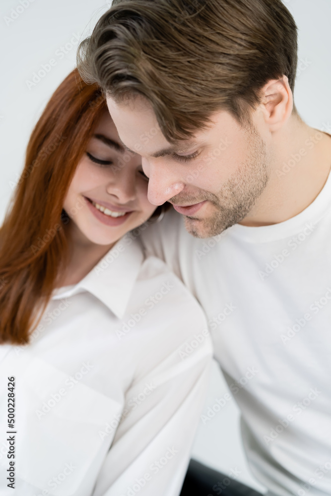 Young man looking away near blurred girlfriend in shirt isolated on white. Young man looking away near blurred girlfriend in shirt isolated on white.