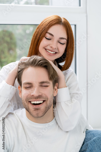 Positive redhead woman touching boyfriend at home.