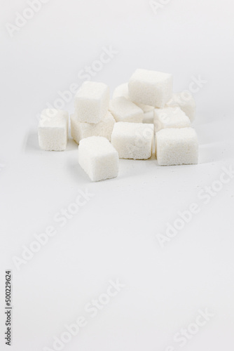 Heap of sugar cubes on white background, place for text