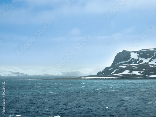 Antarctica ocean waves with snow mountain and white clouds