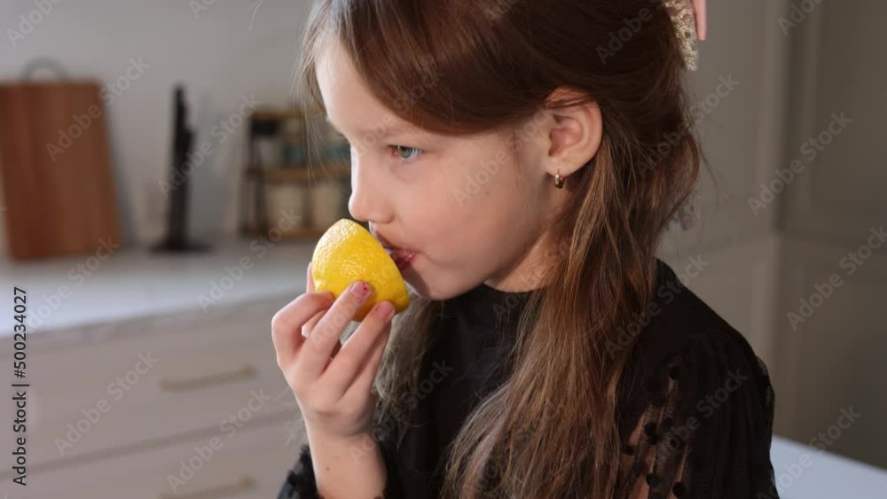 Little baby girl trying and showing lemons in kitchen at home. Child in black holiday dress playng and joking with frits. Happiness and joy cooking and living healthy life Little baby girl trying and showing lemons in kitchen at home. Child in black holiday dress playng and joking with frits. Happiness and joy cooking and living healthy life
