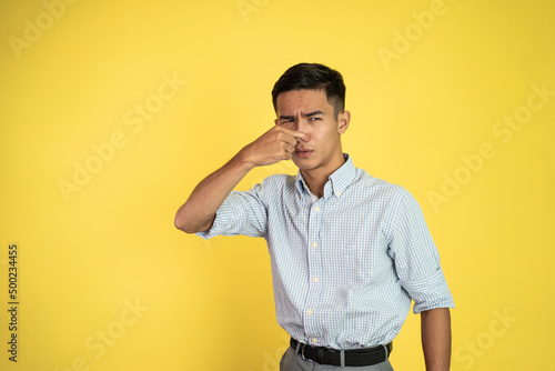 portrait of asian young man cover his nose and feeling disgusted by the smell
