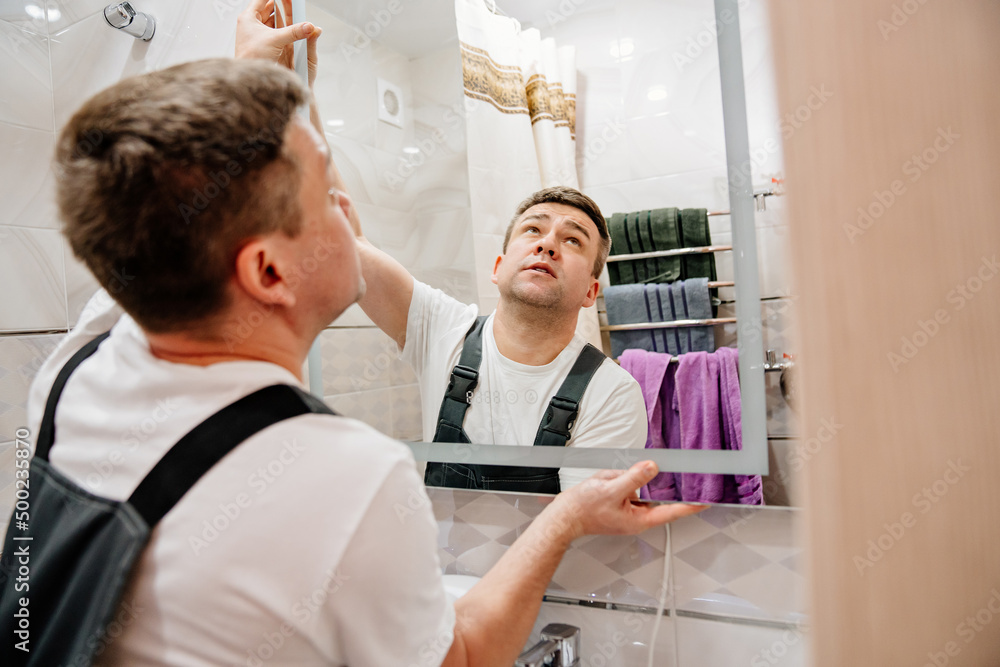 Obraz premium repairman hangs a modern electronic bathroom mirror.