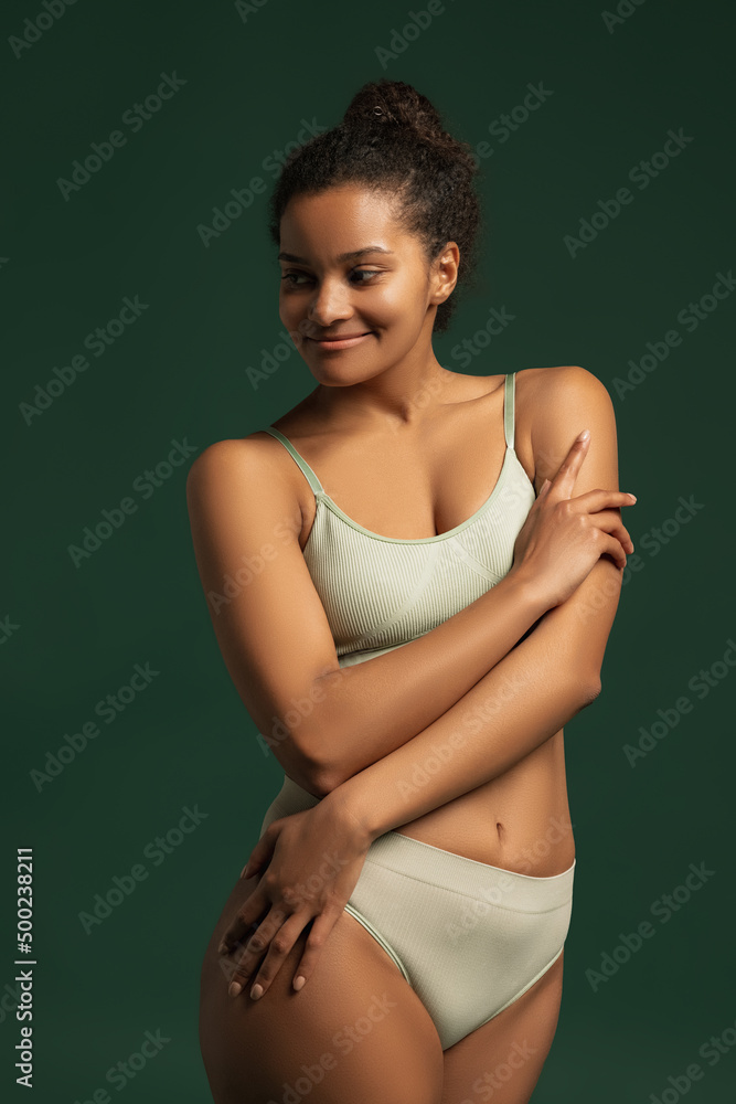 Portrait of young beautiful woman posing in comfortable cotton underwear isolated over green studio background. Self-love concept Portrait of young beautiful woman posing in comfortable cotton underwear isolated over green studio background. Self-love concept