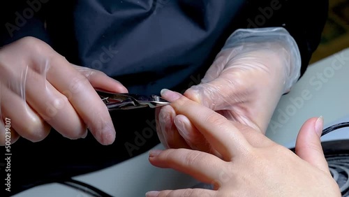 close-up of the manicure master's hands holding the nail clippers negates excess skin photo