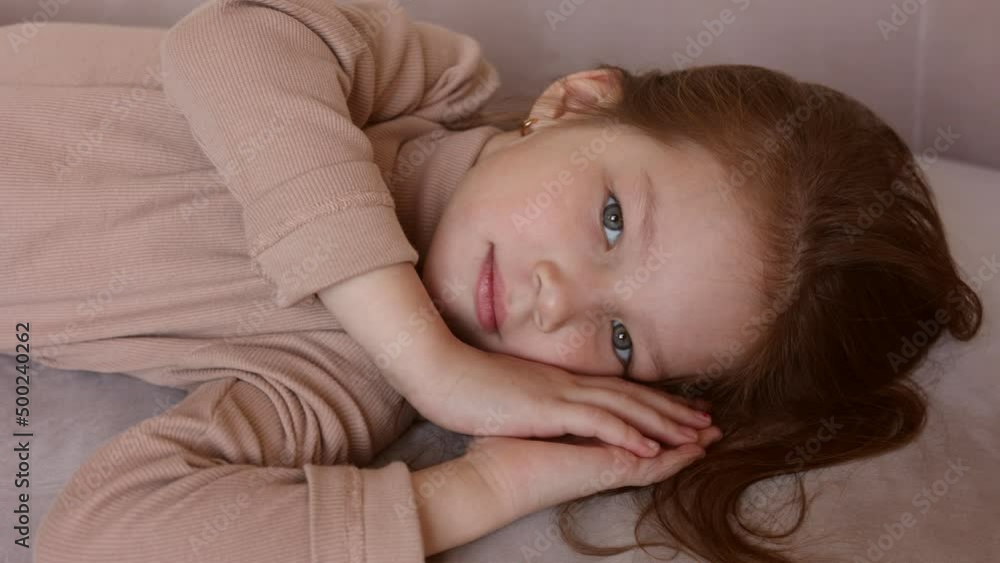 Portrait of 6-year-old little girl laying on her back in casual outfit, on sofa at home. Female child pretty face with beautiful deep eyes. Cute baby girl smiling. Relax and peace. Turtleneck clothes Portrait of 6-year-old little girl laying on her back in casual outfit, on sofa at home. Female child pretty face with beautiful deep eyes. Cute baby girl smiling. Relax and peace. Turtleneck clothes