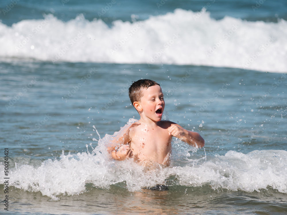 happy child seen from the front having fun with the waves of the sea