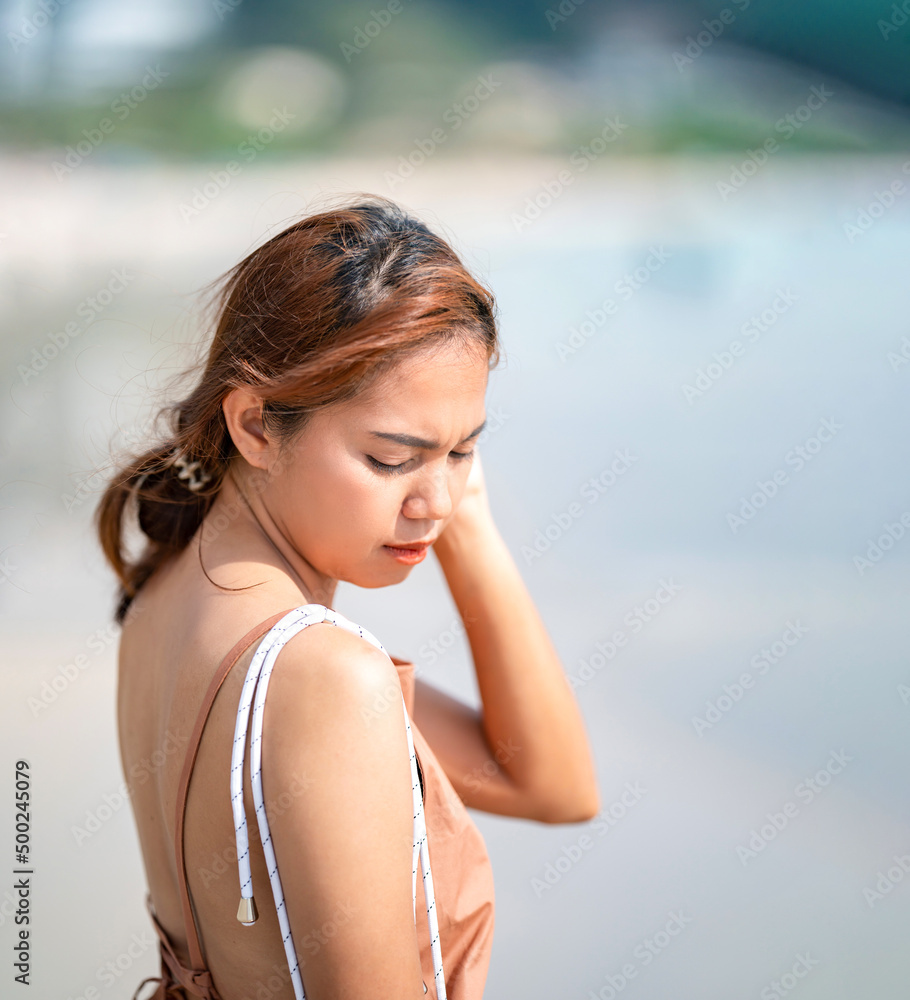 Beautiful Relaxed Thai Woman poses on the beach in the sunlight  with happiness and relaxation.