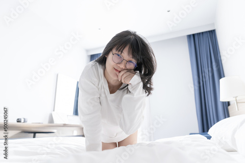 Asian  Japanese  Chinese  Thai woman posed like a cat character whit cute claw action on the bed and looks at the camera.