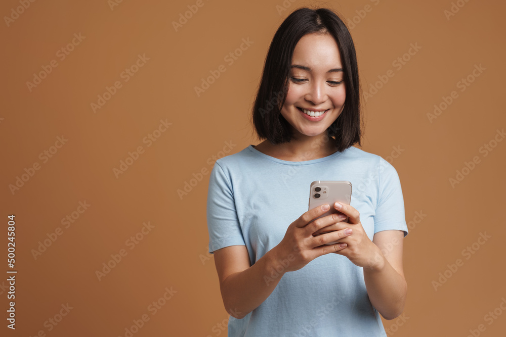 Young asian woman wearing t-shirt laughing while using mobile phone Young asian woman wearing t-shirt laughing while using mobile phone