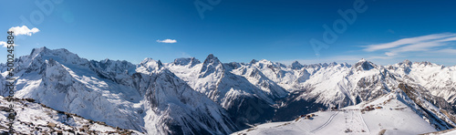 Panoramic view of winter snowy mountains in Caucasus region in Russia with blue sky © SDF_QWE