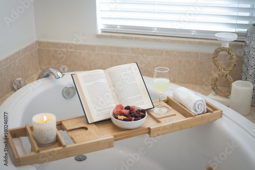Bamboo bath caddy tray with book, candle and fruit photo