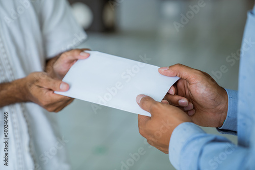 close up of a hand giving envelope as a charity donation at the mosque during ramadan photo