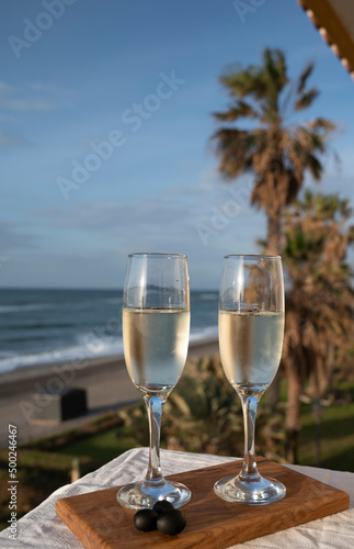 Glasses of Spanish cava sparkling wine and view on blue sea and sandy beach, Costa del Sol vacation destination, Andalusia, Spain