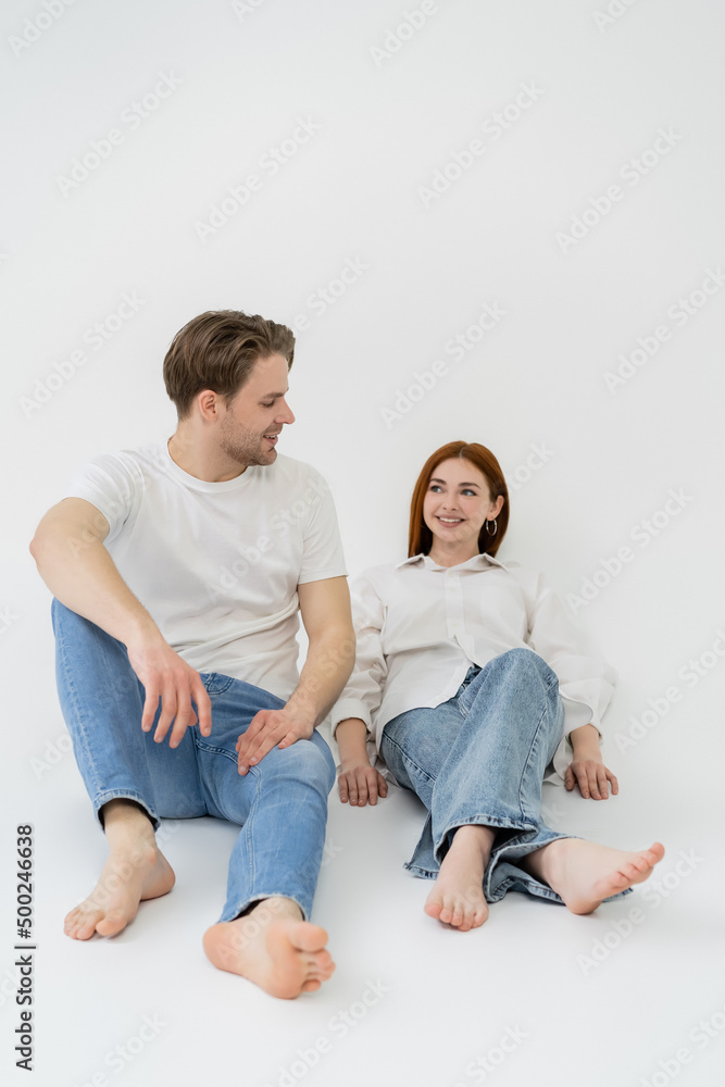 Positive barefoot couple sitting on white background. Positive barefoot couple sitting on white background.
