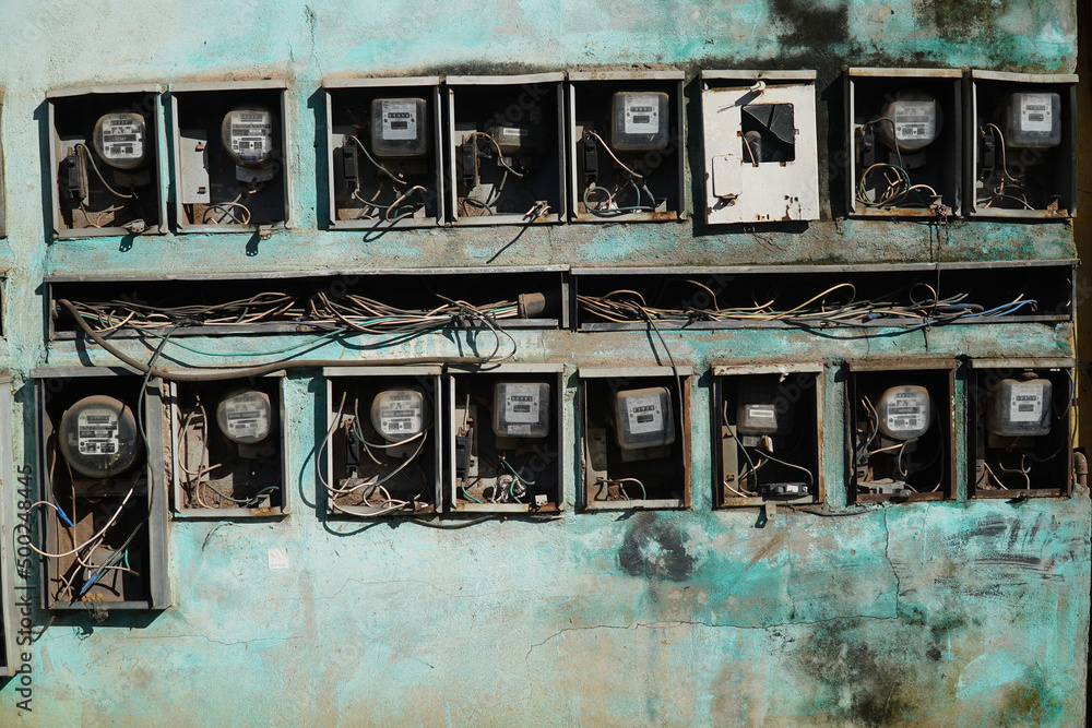 Old electricity meters in a small village in Amazonas, Brazil. Electrical counters in use for different houses on a turquoise green wall, Cacau Pirera, Manaus, Brazil