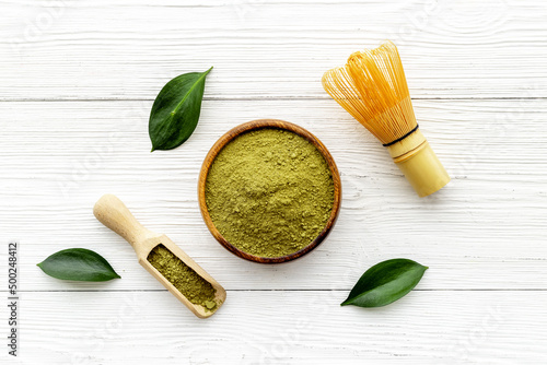 Green matcha powder in bowl with bamboo whisk