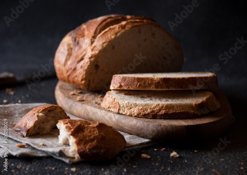 Loaf of bread freshly baked and cut on dark background photo