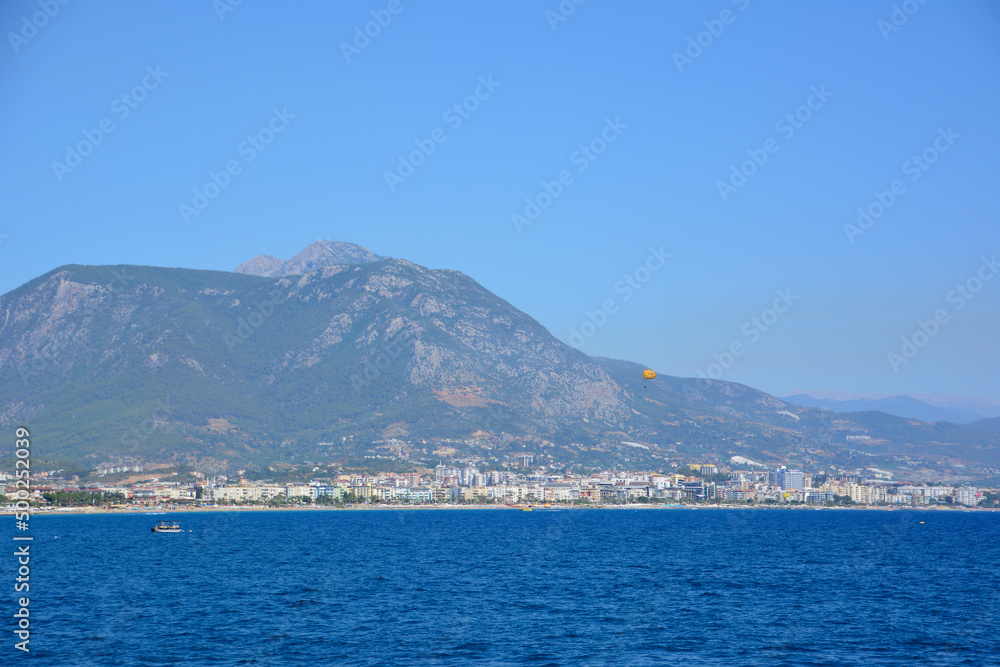 mediterranean sea with clear sky and parachute on mountains background