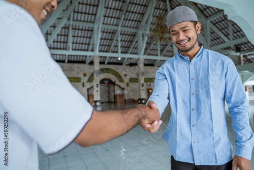 portraito of asian muslim people shaking hand at the mosque photo