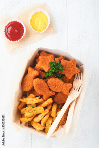 Fish and Chips british fast food. Fish Sticks with french fries set on takeaway paper plate on white wooden background. Traditional British authentic street food or takeaway food. Mock up.