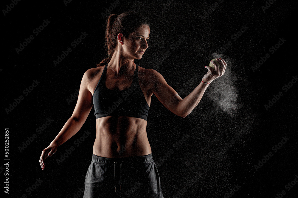 Tennis player girl with magnesium powder on her hands grabbing a ball. Dust visible..