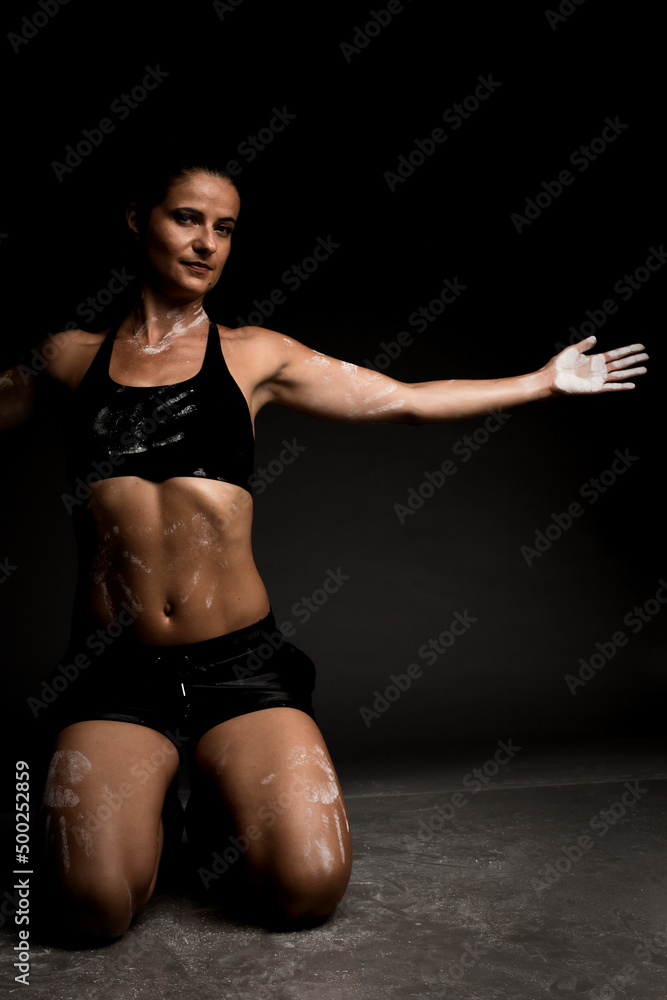 Obraz premium Sexy fit girl in sportswear on the ground. Magnesium powder prints of hands on her body..