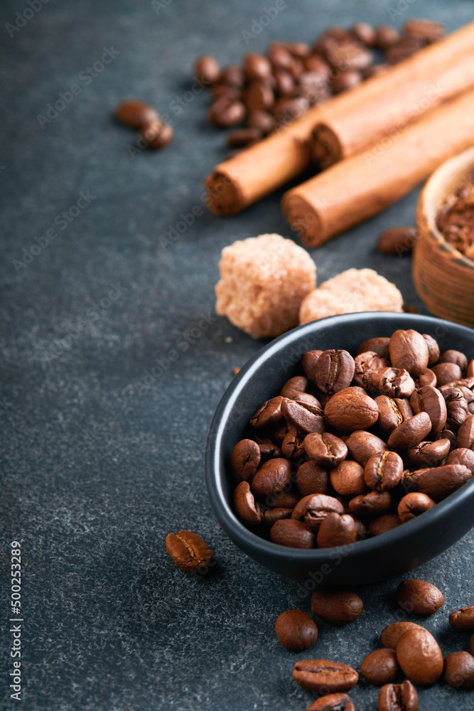 Fototapeta premium Coffee beans background. Roasted Coffee concept with differents types of coffee, beans and cinnamon sticks on dark black stone background. Top view. Coffee concept. Mock up.
