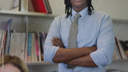 Tilt-up steady shot of a beautiful attractive young multiethnic couple of businesspeople standing in front of a bookcase in the office.  photo