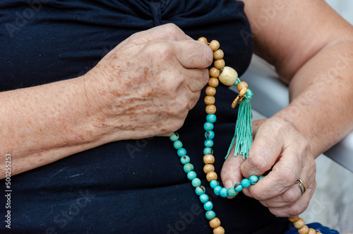close up on senior woman hands praying with a chaplet, rosary